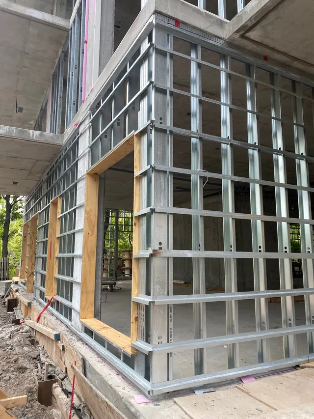 A building corner with Z-bars wrapping the steel studs and plywood bucks at the openings