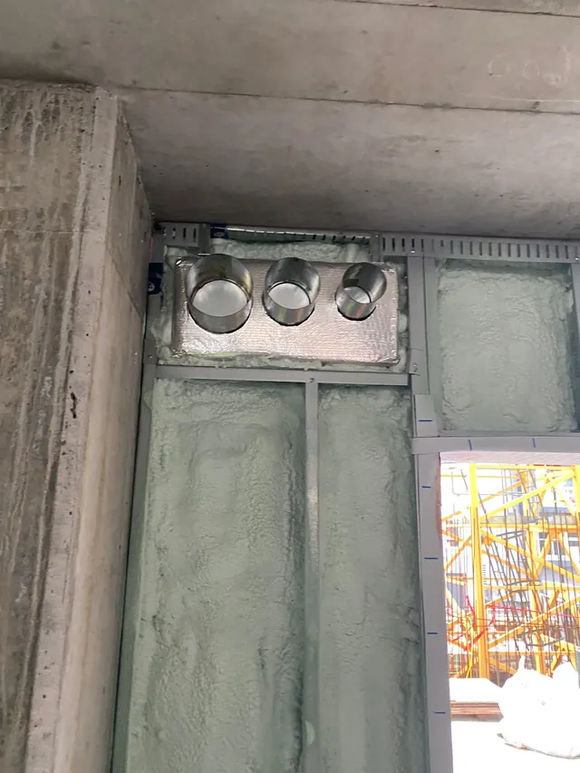 Duct sleeves through the exterior wall, sealed into the foam