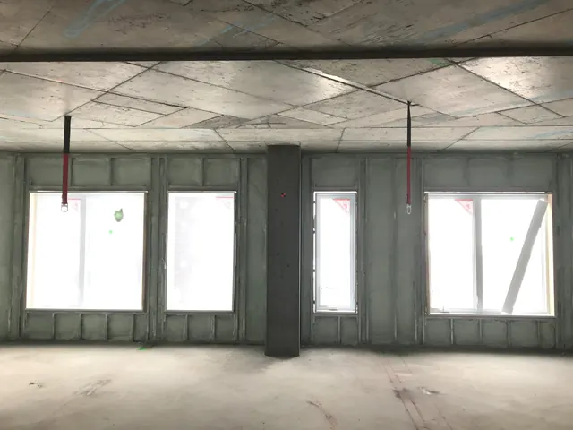 An open floor with foam on every exterior wall and the windows installed