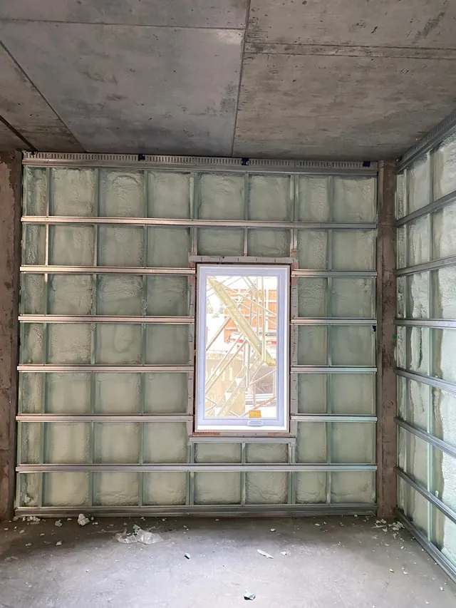 Interior furring channels over the foamed wall, around a window