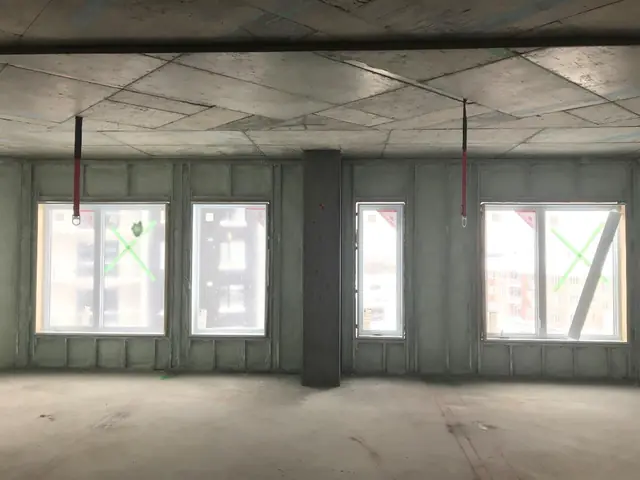 An open floor with foamed exterior walls and windows, before drywall