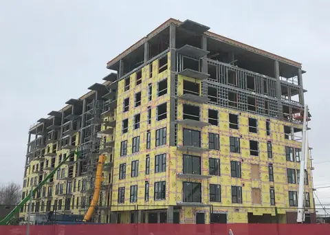 Nicolas Project: a mid-rise building with yellow sheathing and window openings