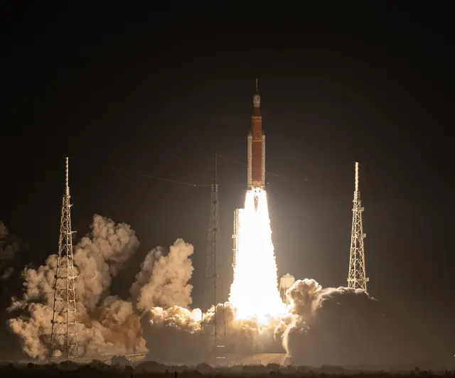 The Space Launch System lifting off at night on a column of fire